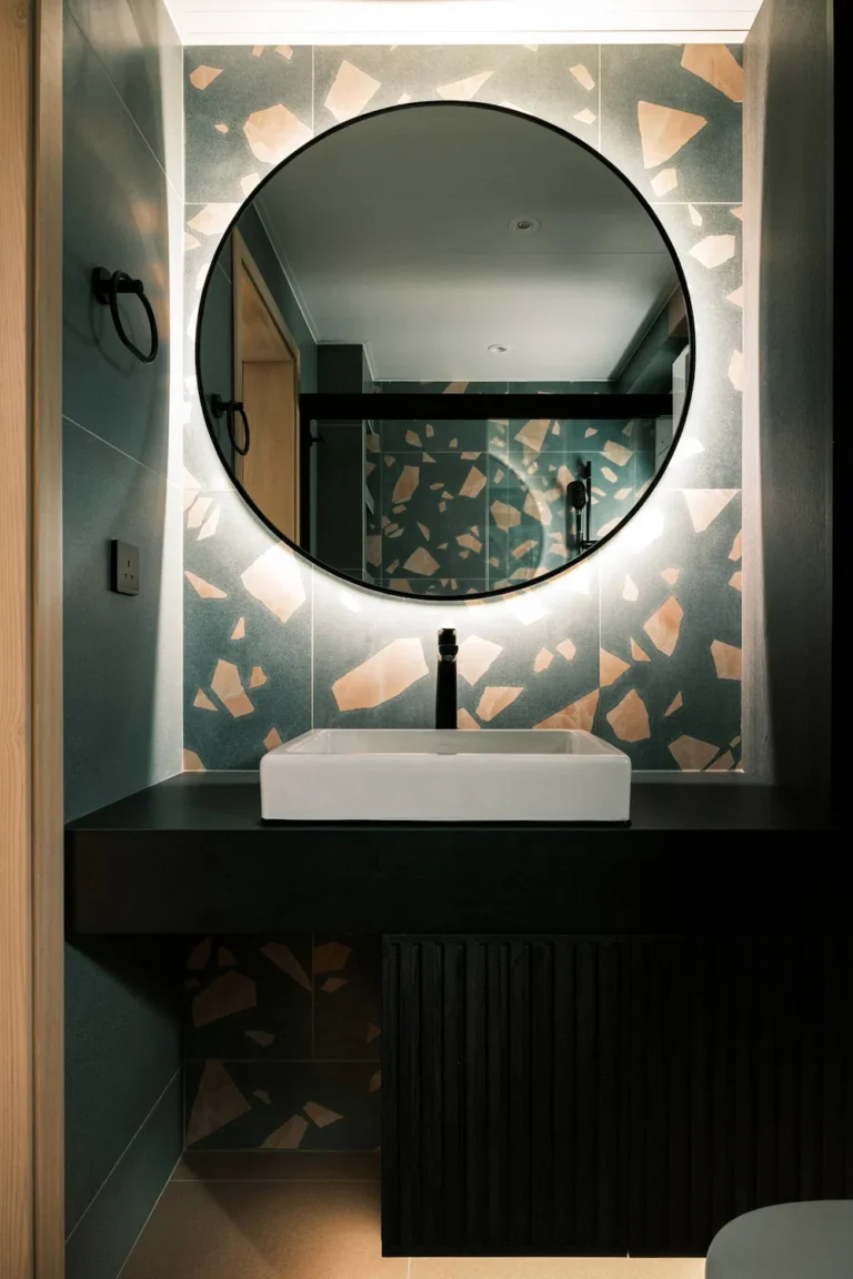 Bathroom design with patterned tiles and round mirror