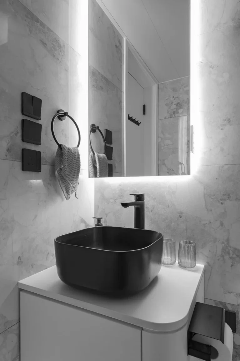 Bathroom with grey tile, black sink and mixer, and white cabinet